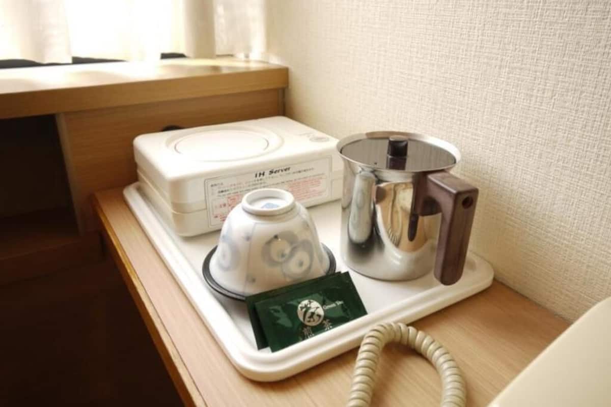 A hotel room with a minibar, a coffee maker, and a telephone on a bedside table.