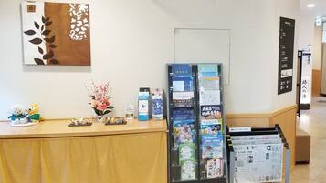 A reception desk with a bulletin board displaying various items, a vase with flowers, and a wall-mounted artwork.