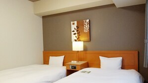 Een hotelkamer met twee eenpersoonsbedden, een houten hoofdbord, een nachtkastje met een lamp en een aan de muur hangend kunstwerk.