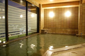 A spa area with a tiled wall, a bench, and a glass partition reflecting lights. - Hotel Route Inn Kanazawa Ekimae (Kanazawa)