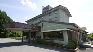 Een hotel met een overdekte ingang, meerdere ramen en een naambord.