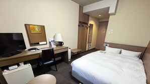 Een hotelkamer met een bed, bureau, stoel, televisie en een klein tafeltje.