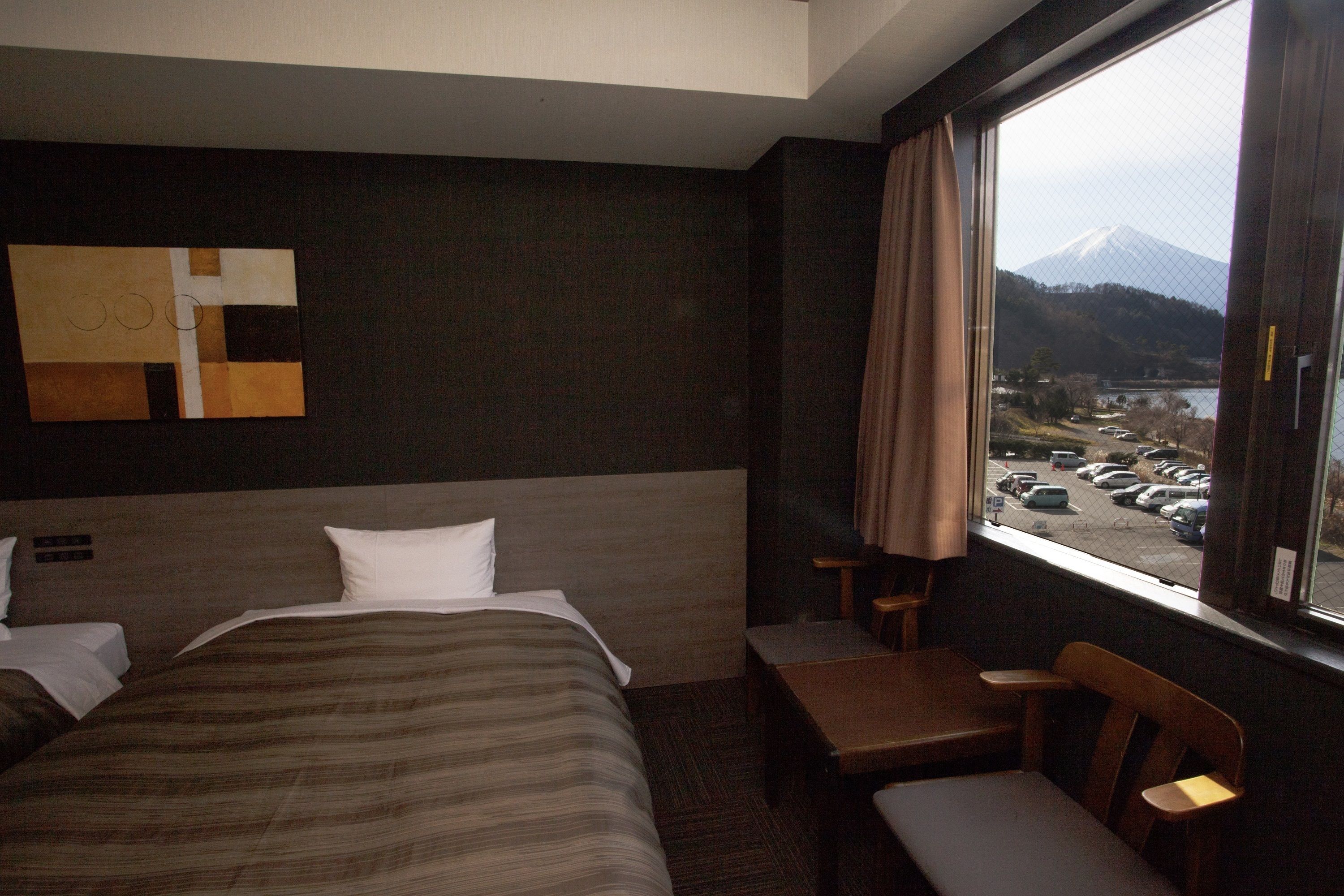 Une chambre d’hôtel avec un lit, un bureau et une vue sur la montagne.