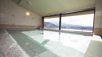 An indoor swimming pool with a view of mountains through large windows.