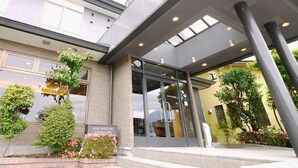 A modern hotel entrance with a covered walkway, glass doors, and a sign indicating it is the Hotel Route Inn in Kawaguchiko. - Hotel Route - Inn Kawaguchiko (Fujikawaguchiko)