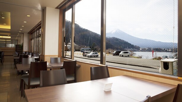 A restaurant with large windows offering a view of a mountain and a parking lot. - Hotel Route - Inn Kawaguchiko (Fujikawaguchiko)