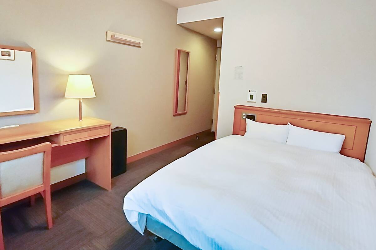 Ein Hotelzimmer mit Bett, Schreibtisch, Stuhl und Lampe.