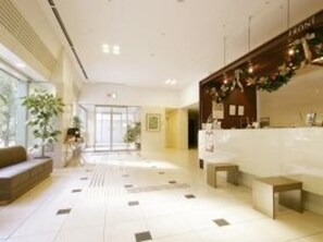 A hotel reception area with a reception desk, seating area, and a large window providing natural light. - Hotel Route Inn Osaka Honmachi (Osaka)