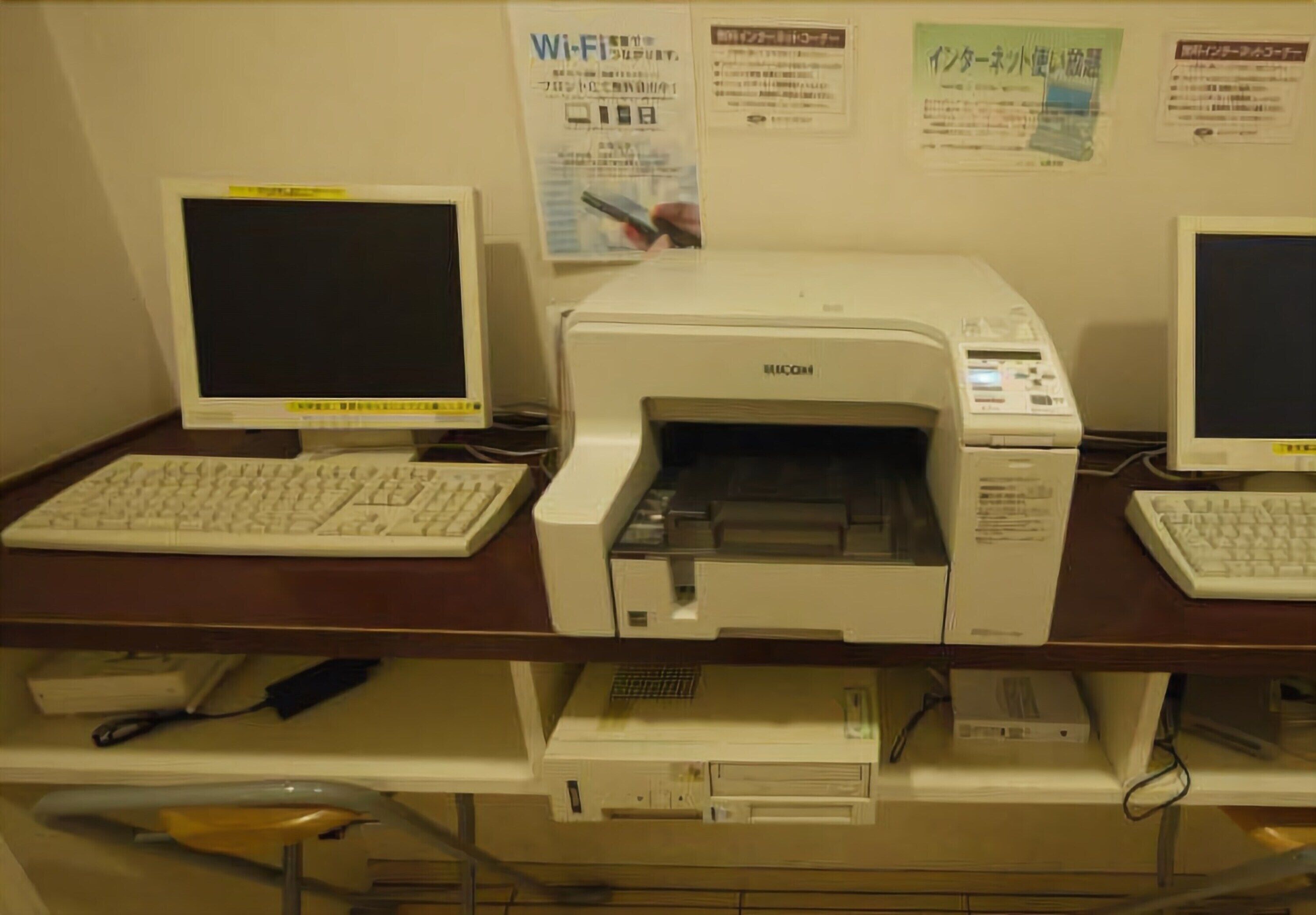 A desk with a computer, two monitors, and a printer.