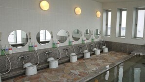 A row of sinks with mirrors, soap dispensers, and faucets in a bathroom with stone flooring and large windows. - Hotel Route Inn Osaka Honmachi (Osaka)