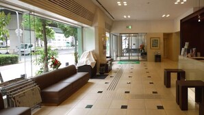 A hotel lobby with a sofa, tables, and a tiled floor. - Hotel Route Inn Osaka Honmachi (Osaka)