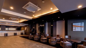 A spacious lobby with a reception desk, multiple seating areas, and a large artwork on the wall. - Hotel Route-Inn Grand Tokyo Toyocho (Tokyo)