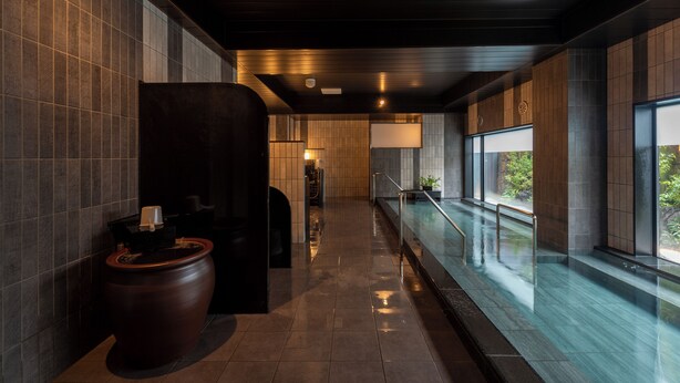 A modern indoor pool area with a long corridor, a large wooden planter, and a view of greenery outside. - Hotel Route-Inn Grand Tokyo Toyocho (Tokyo)