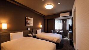 A hotel room with two beds, a desk with a chair, a small table, a lamp, and a painting on the wall. - Hotel Route-Inn Grand Tokyo Toyocho (Tokyo)