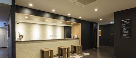 A reception area with a check-in counter, a reception desk, and a seating area with stools.