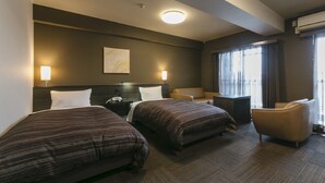 Ein Hotelzimmer mit zwei Betten, einem Schreibtisch, einem Stuhl und einem großen Fenster mit Vorhängen.