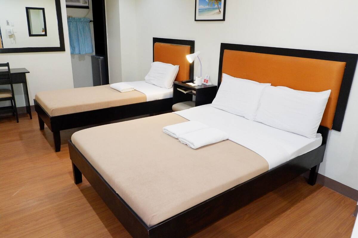 A hotel room with two single beds, a desk, and a chair.