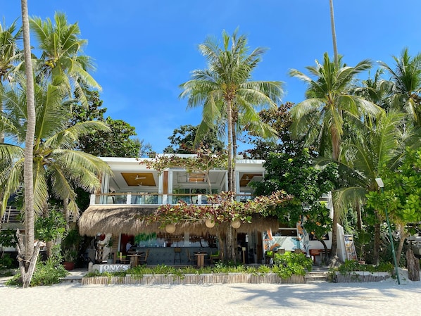 A beachfront property with a thatched-roof bar, outdoor seating, and palm trees. - Jony's Beach Resort (Boracay Island)