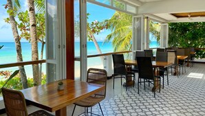 Un comedor con mesas y sillas, ventanas grandes y vistas al océano.