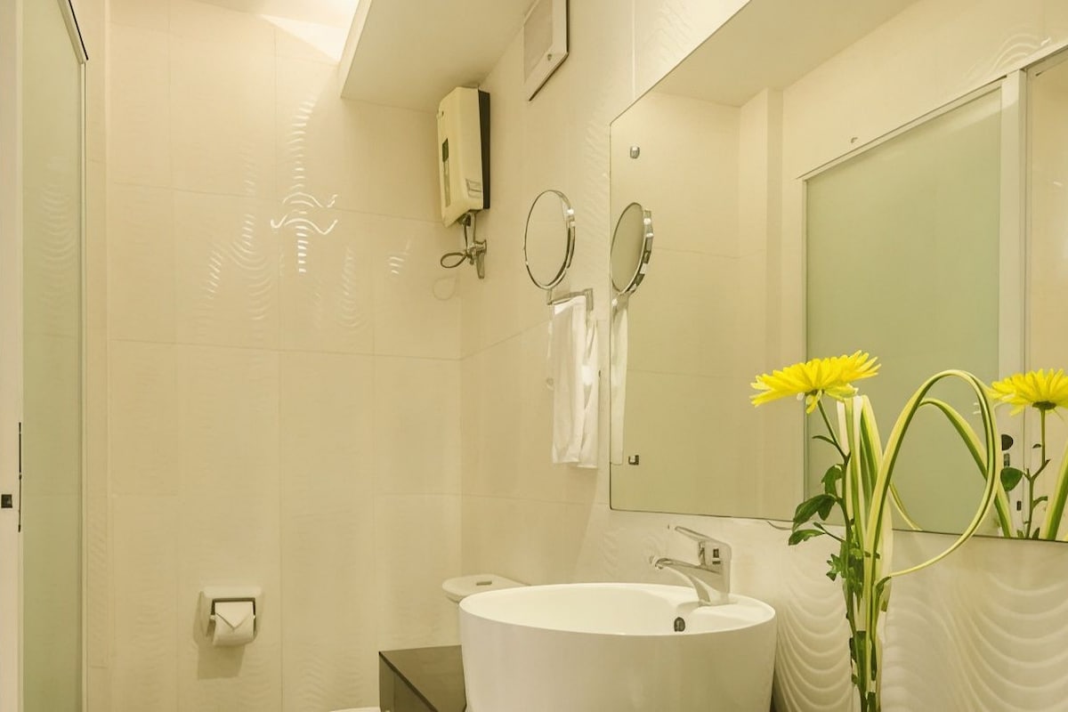Un baño con un lavamanos blanco, un espejo y un perchero para toallas.