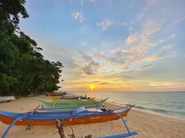 A beach with boats and a sunset.