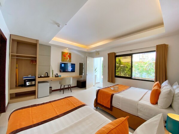 A hotel room with two beds, a desk, a television, and a window with curtains. - Jony's Beach Resort (Boracay Island)