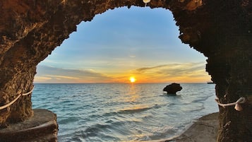 Eine natürliche Felsformation mit freiem Blick auf den Sonnenuntergang über dem Meer.