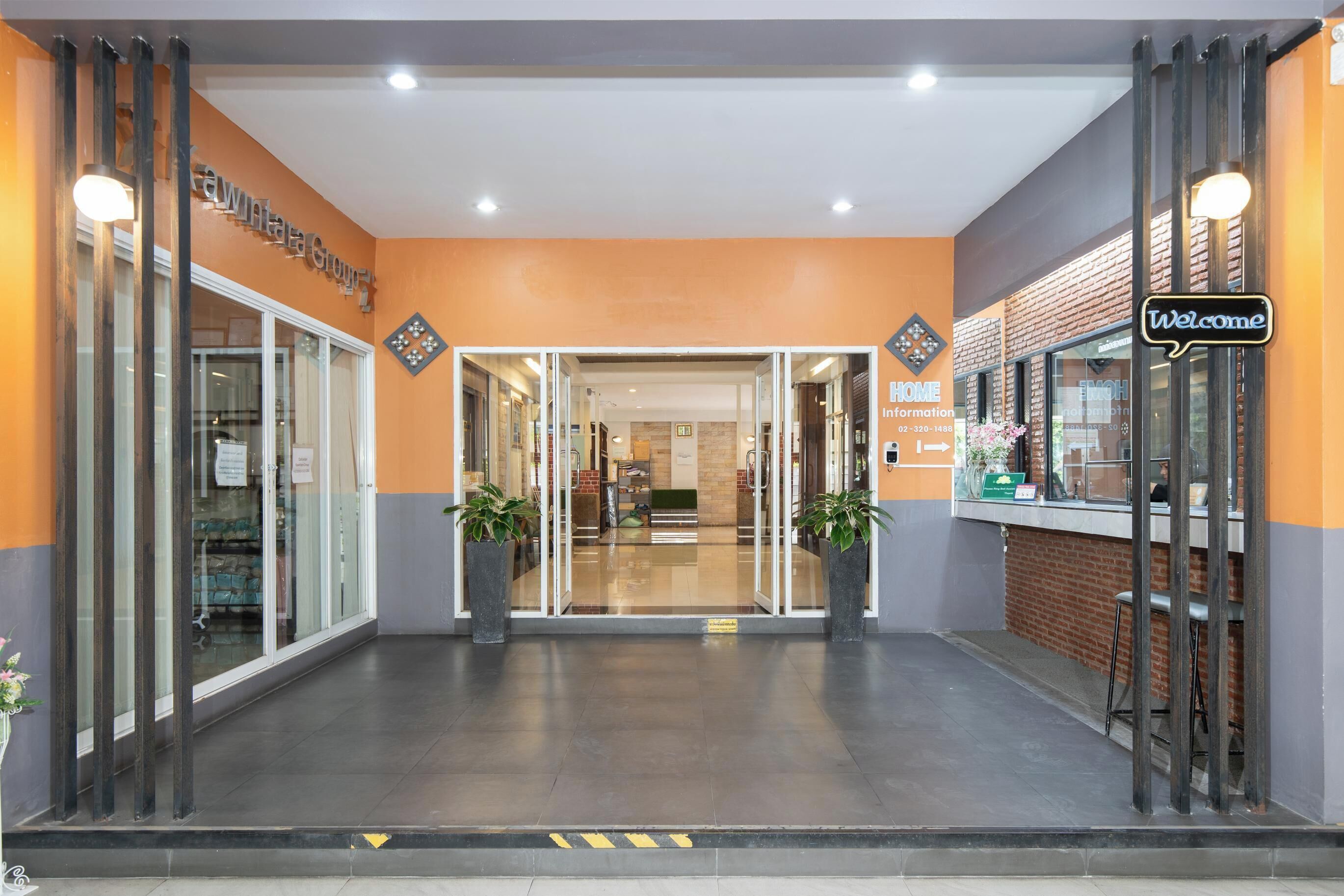 L’entrée d’un hôtel, avec des portes en verre, un comptoir d’accueil et une pancarte « Bienvenue ».