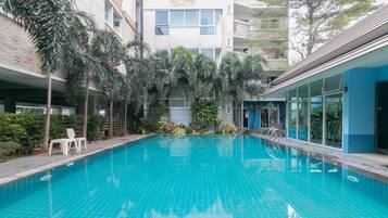 Relax by the serene pool surrounded by lush greenery and potted plants.