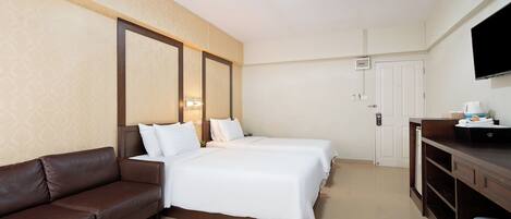Une chambre d’hôtel avec un lit, un canapé marron, une télévision et un bureau avec un ordinateur.
