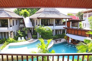 Relax by the resort's central pool surrounded by lush greenery and comfortable lounge chairs.