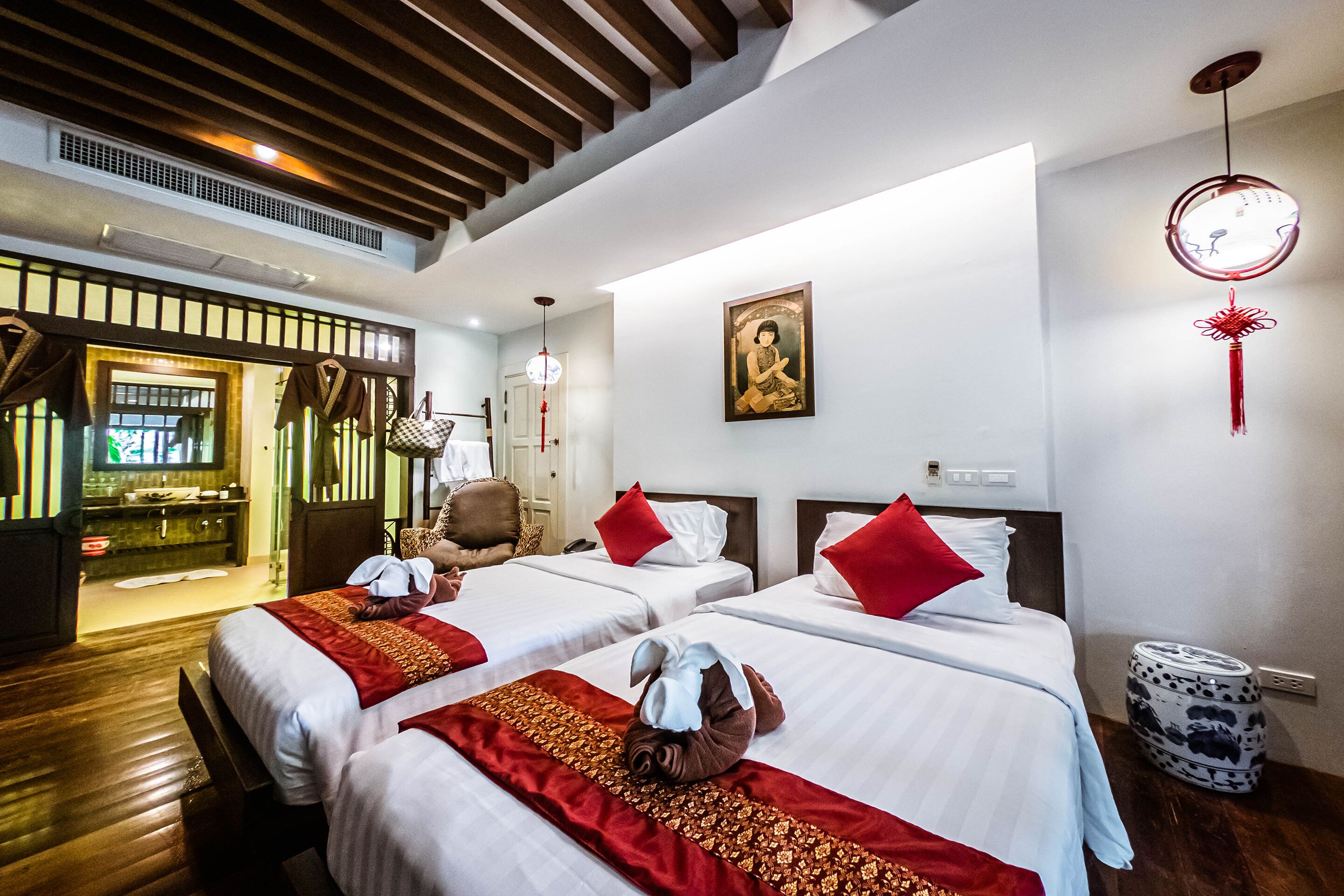 Habitación de hotel con dos camas, zona de estar, baño y vistas al exterior.