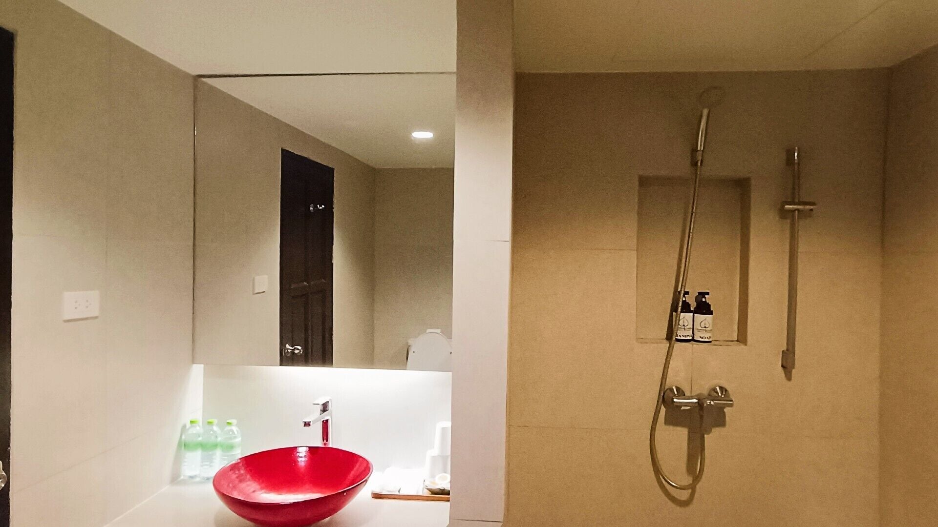 Un baño moderno con un lavabo rojo, ducha y espejo.