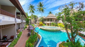 Un resort con piscina, sillones de descanso y exuberante vegetación tropical.