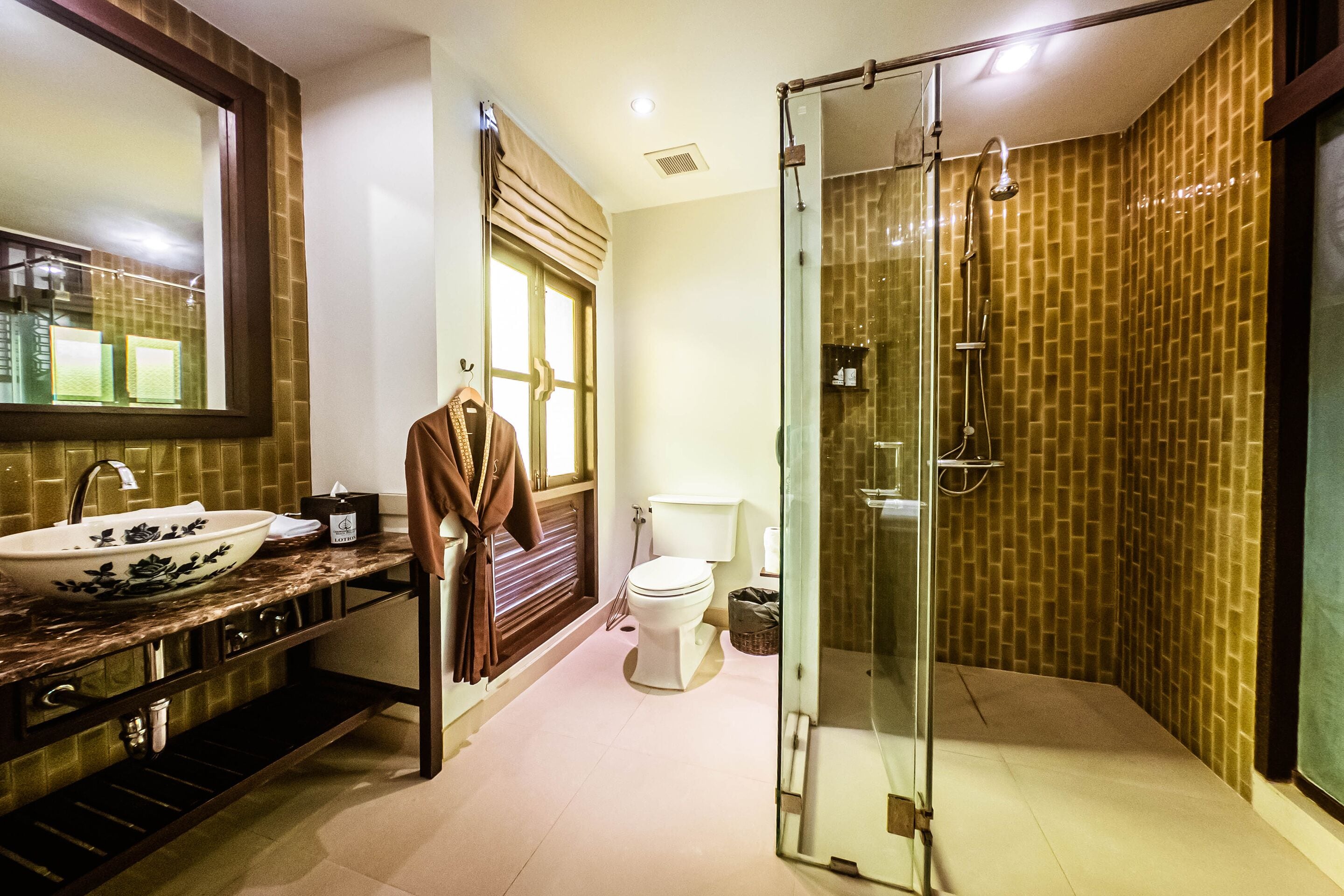 Une salle de bain avec une douche à parois de verre, un lavabo avec un receveur, des toilettes et un miroir.
