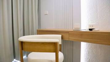 Un bureau en bois, une chaise blanche, une prise de courant et une fenêtre avec des stores.