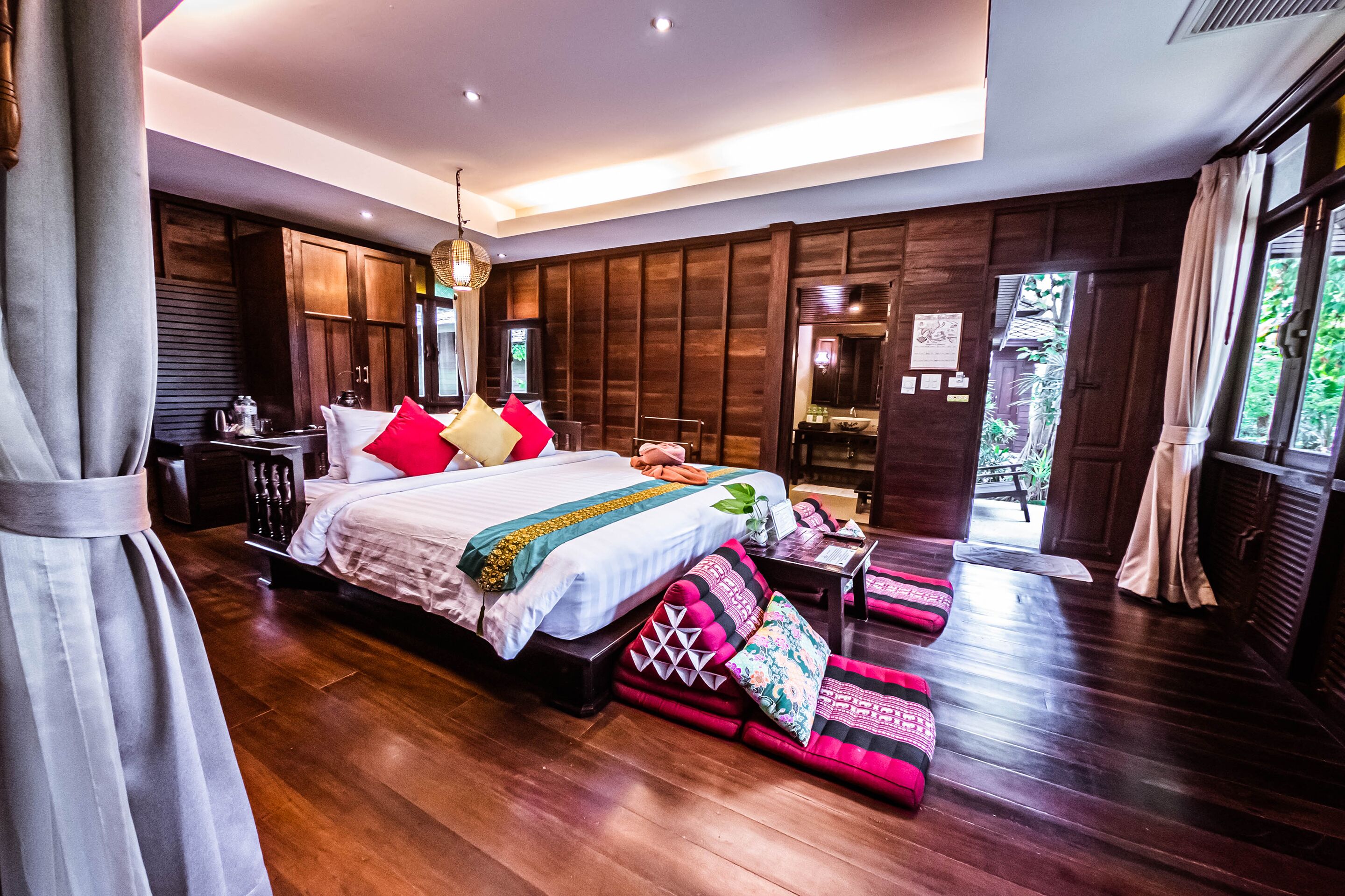Un dormitorio amplio con una cama grande, piso de madera y vistas al exterior.