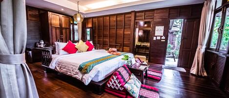 Un dormitorio amplio con una cama grande, piso de madera y vistas al exterior.