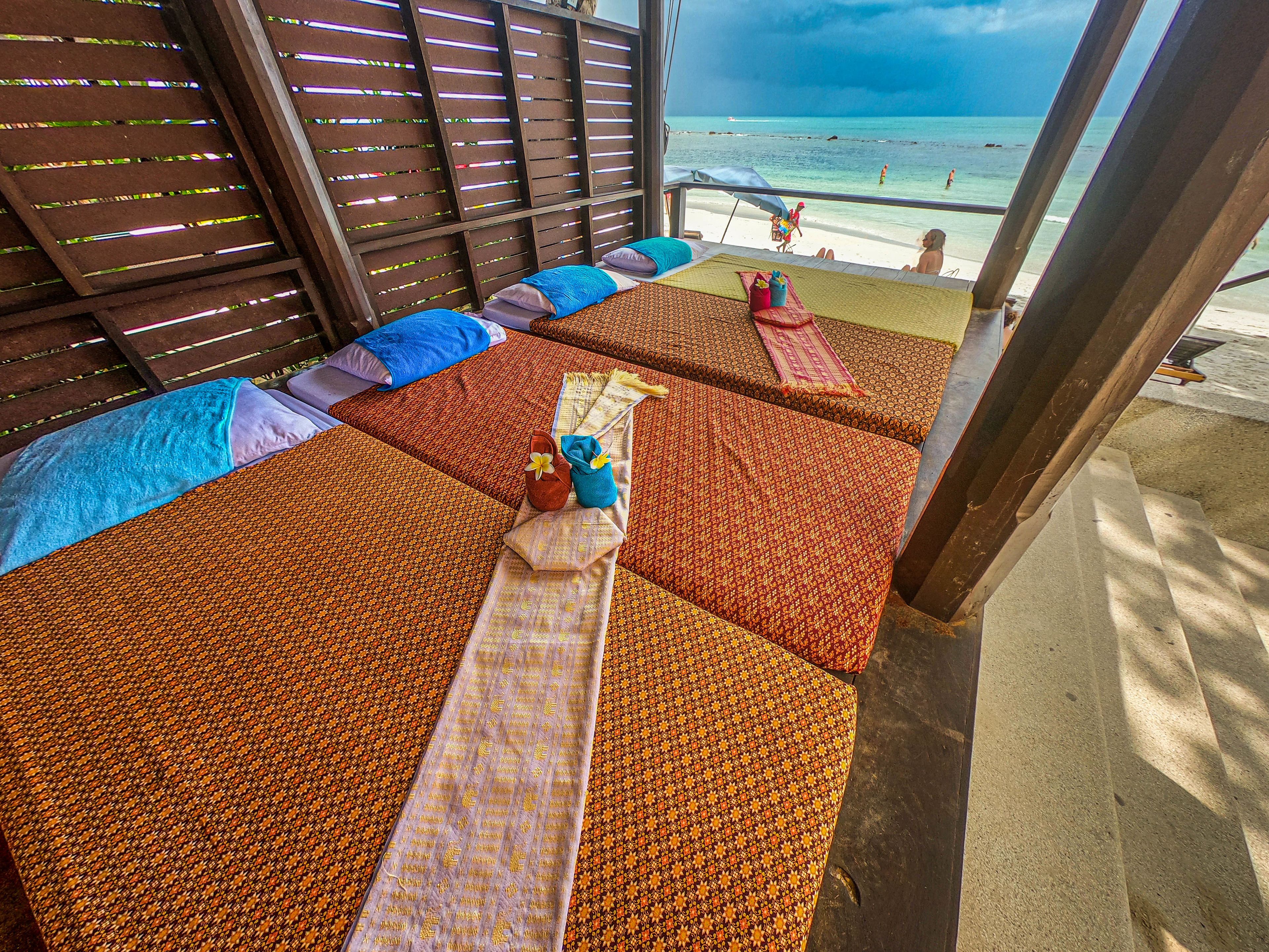 A beachside room with multiple beds, a view of the ocean, and a wooden partition.
