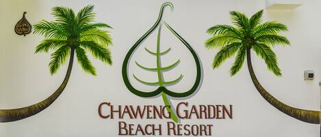 A sign for Chaweng Garden Beach Resort with palm tree graphics and the resort's name.