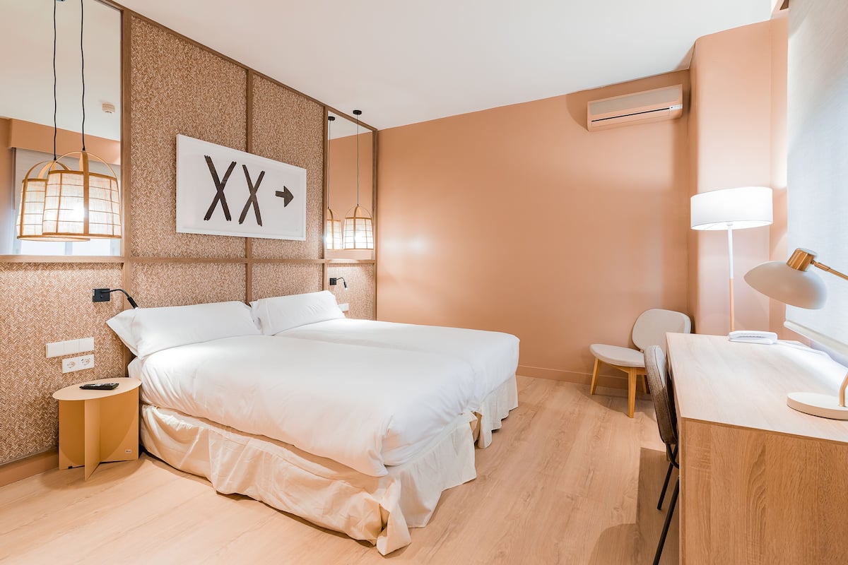 A modern hotel room with a large bed, bedside tables, a desk, and a chair.