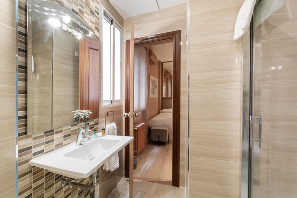 Un baño moderno con un espejo grande, dos lavamanos y una ducha.
