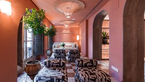 A hallway with patterned ottomans, a potted plant, a sofa with cushions, and a large pot. - U-Sense Granada Centro (Granada)