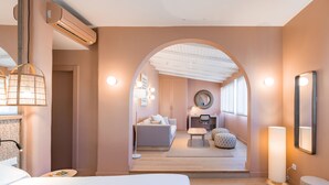 A modern hotel room with a large bed, a desk, a sofa, and a small table. There is a mirror on the wall and a lamp on the desk. - U-Sense Granada Centro (Granada)
