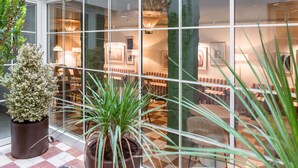 A hotel lobby with a checkered floor, potted plants, and a seating area with tables and chairs. - U-Sense Granada Centro (Granada)