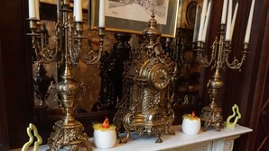 A dining area with ornate candelabras, a framed historical drawing, and a table set with a green tablecloth. - Hotel Asiris (Bruges)
