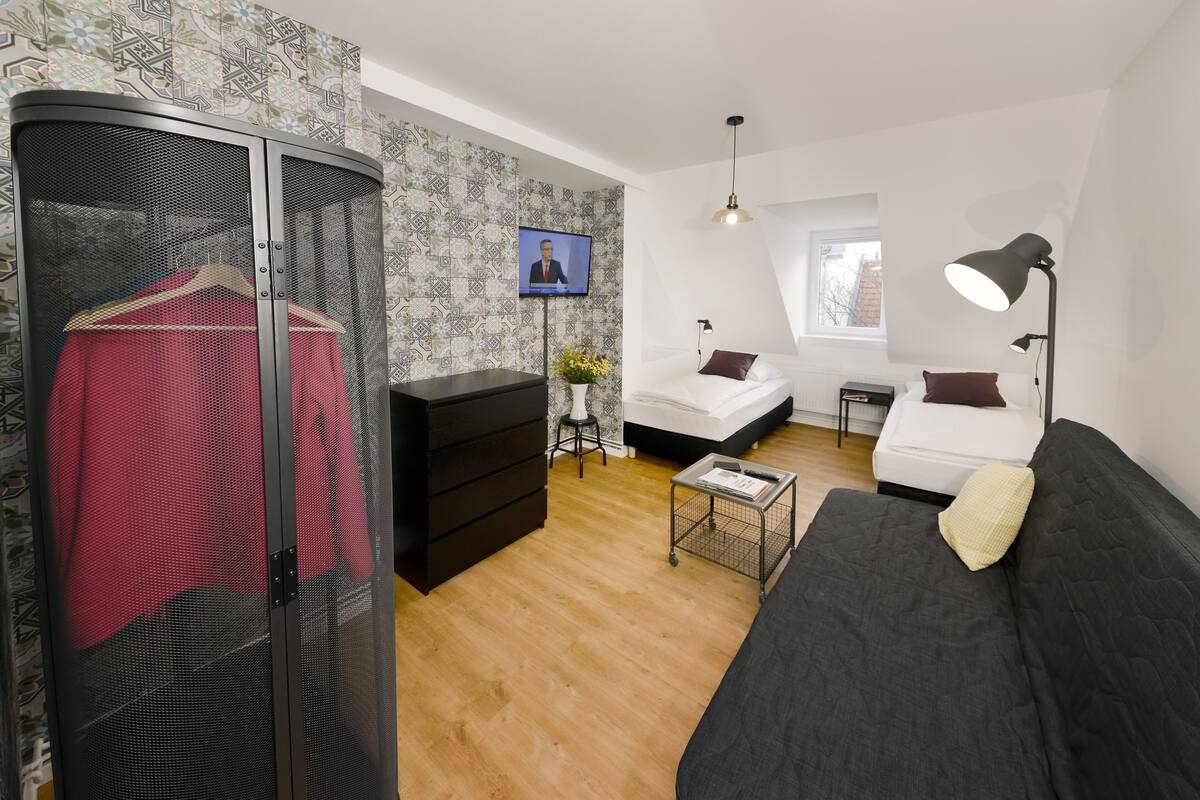 Ein modernes Schlafzimmer mit Kleiderschrank, Bett, Sofa und Fernseher.