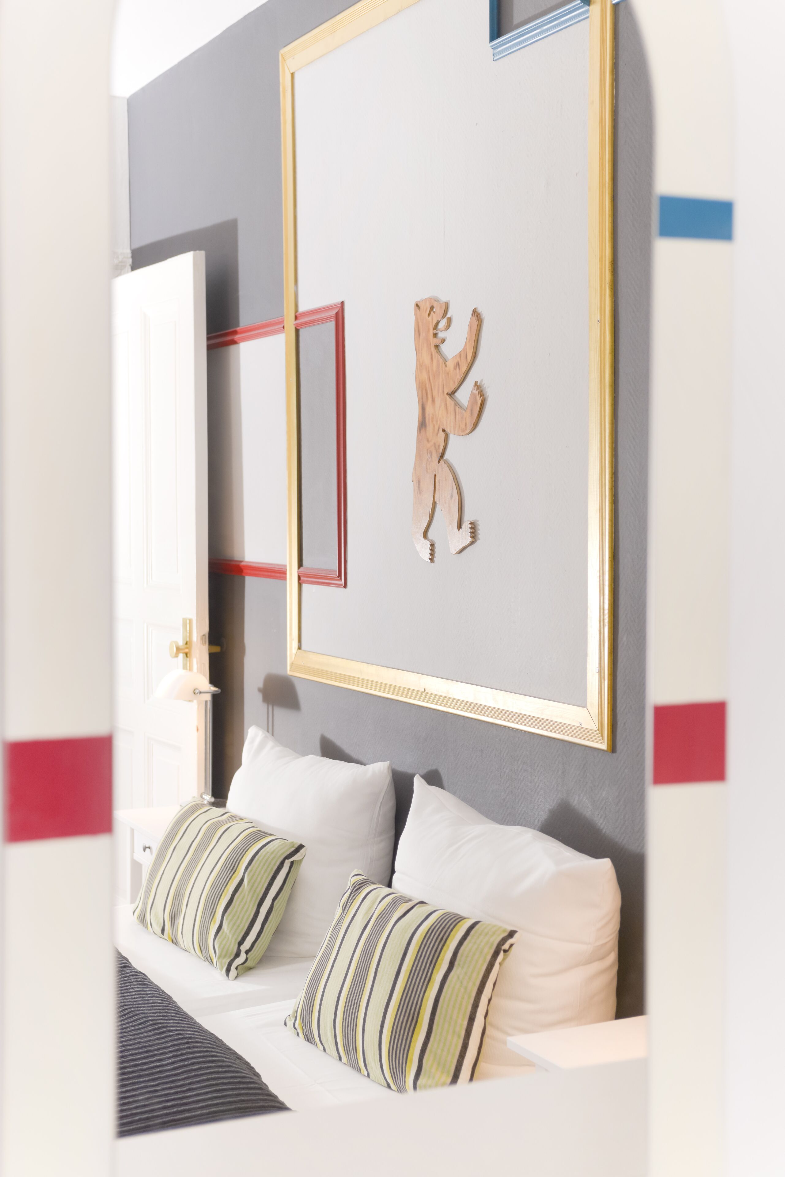 Een slaapkamer met een bed, kussens, een nachtkastje en een lijst met kunst aan de muur.