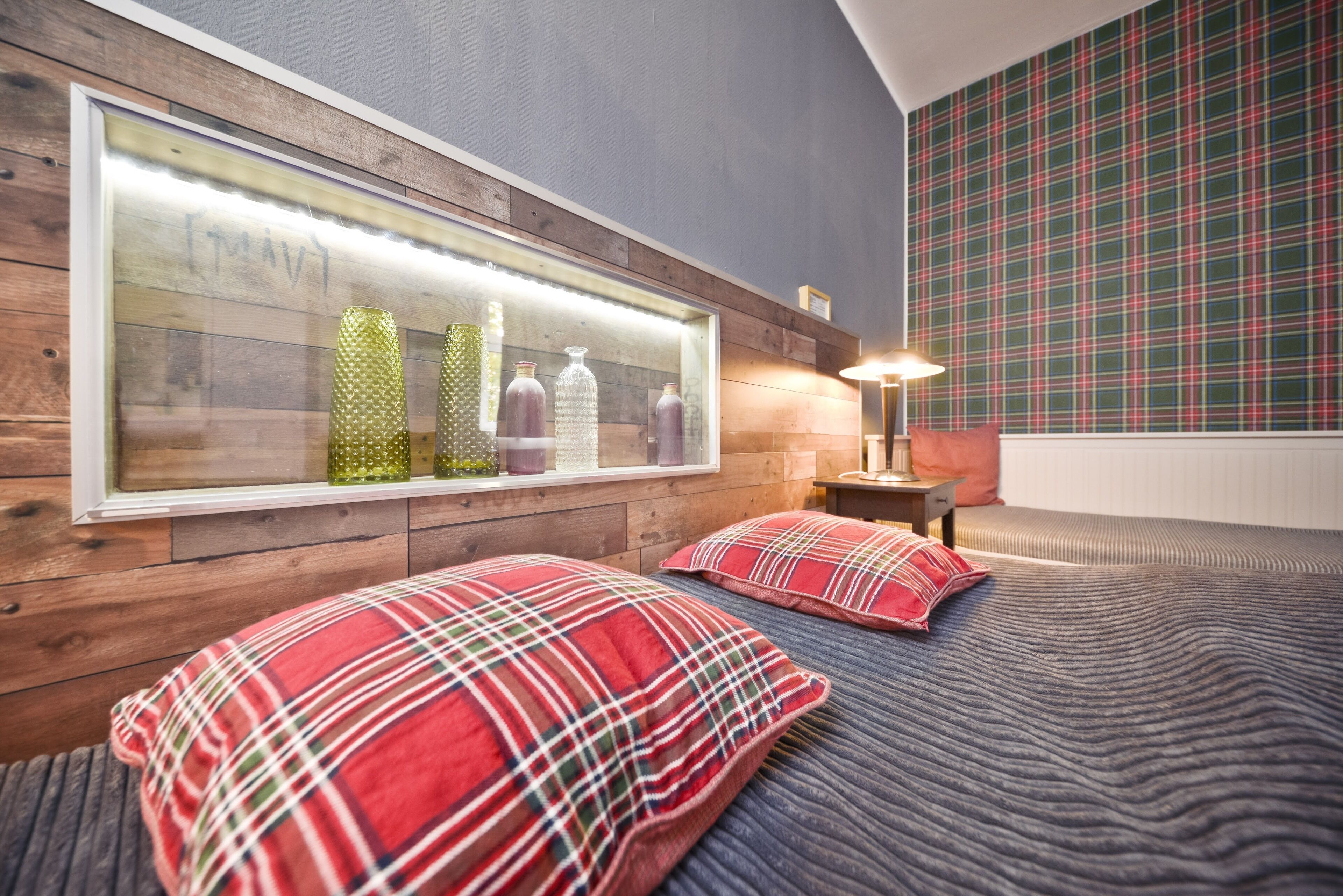 Ein Schlafzimmer mit einem hölzernen Kopfteil, einem großen Spiegel und karierten Kissen.