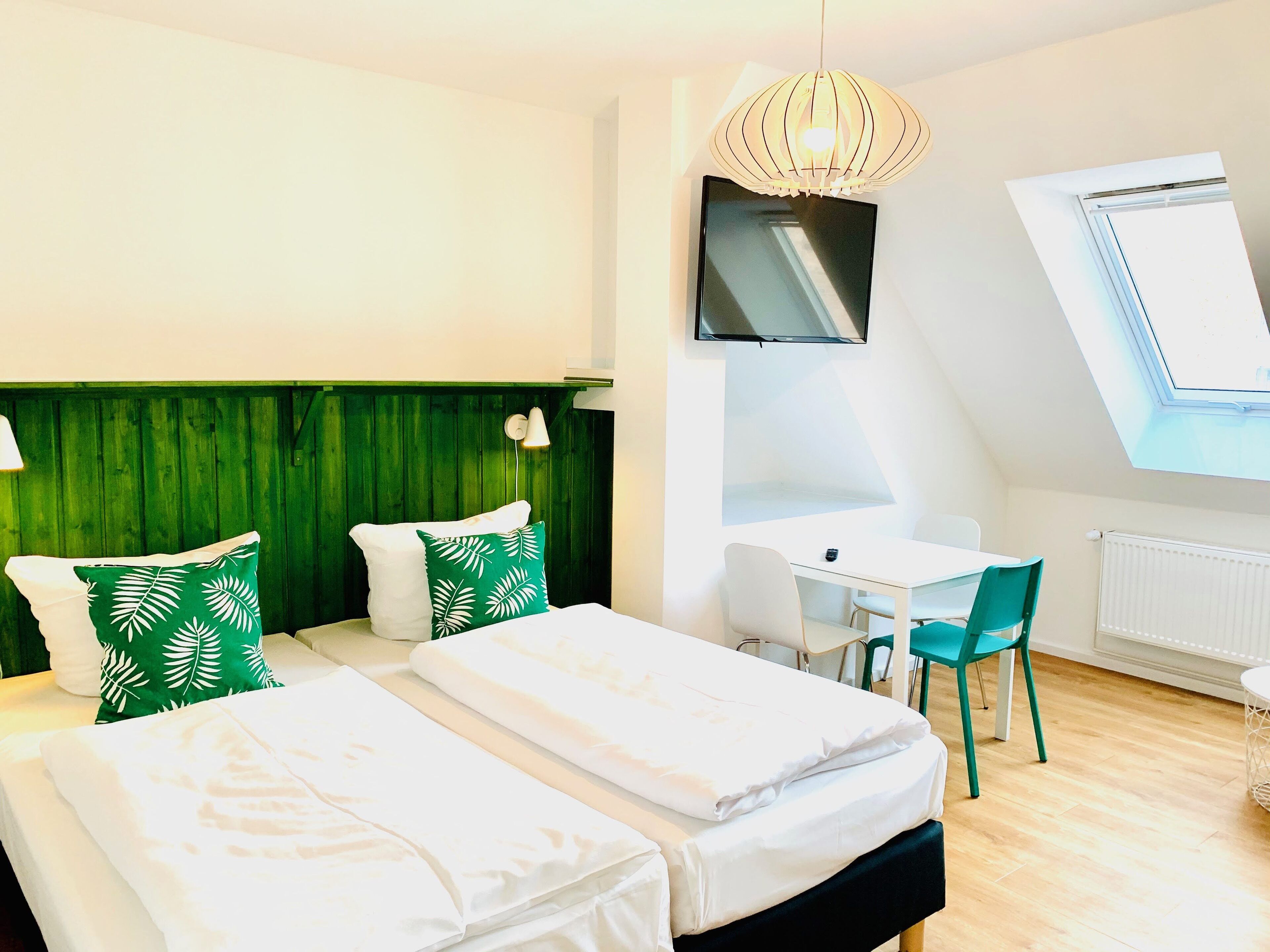 Ein Hotelzimmer mit zwei Betten, einem Schreibtisch, einem Sessel, einem Fernseher und einem Oberlicht.